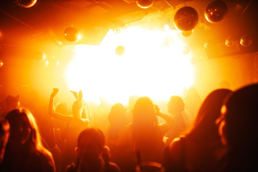A dancer in bunny ears silhouetted against gold light