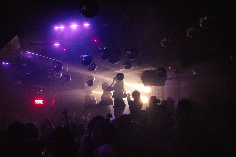 Dancers silhouetted in purple light beside the exit sign